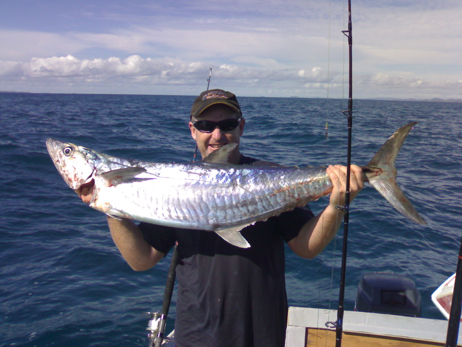 Matt from Higher Deeper Fishing holding a massive Spanish mackerel on the open ocean